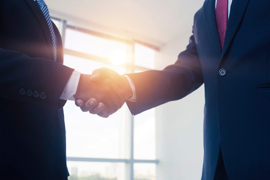 Cropped image of business people shaking hands, backlit
